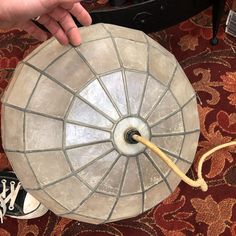 a person is pointing at the top of a table with a light fixture on it