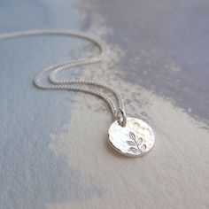 Our delicate Silver Hammered Disc Necklace is 925 Sterling Silver. The tiny silver disc has been gently hammered giving it an interesting texture that reflects the light beautifully. The disc pendant has been hand stamped with a tiny leaf print - a perfect gift for a nature lover! Details: * Necklace length 18'' * The fine curb chain is sterling silver * The tiny disc pendant measures approx. 9mm Your silver disc necklace will arrive carefully packaged and presented in a Silver Willow gift box, making it a perfect gift for a loved one or a special treat for yourself. Matching Silver Disc Earrings available: https://www.etsy.com/uk/listing/1250063904/hammered-silver-earrings See more Jewellery from SilverWillowUK: https://www.etsy.com/uk/shop/SilverWillowUK Thank you for looking! Silver Pendant Necklace Simple, Metal Stamped Necklace, Tiny Pendant Necklace, Silver Layered Necklace, Jewellery Workshop, Pmc Jewelry, Art Clay Silver, Wood Jewelery, Silver Metal Clay