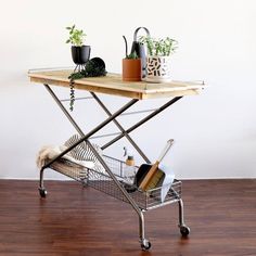 a table that has some plants on it and a basket with brooms in it