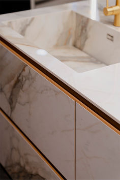 a bathroom sink with marble counter tops and gold faucets