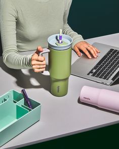 a woman sitting at a desk with a laptop and coffee cup