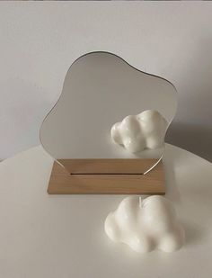 a white cloud shaped object sitting on top of a table next to a wooden stand