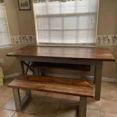 a kitchen table with two benches in front of it and a window behind the bench