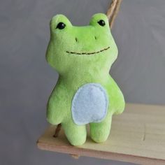 a green stuffed frog sitting on top of a wooden shelf