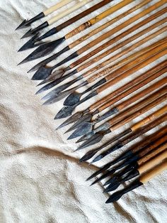 an assortment of wooden and metal arrows laid out on a white cloth