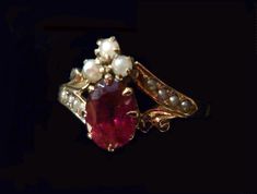 "A royal arrangement of garnet and seed pearls on this elegant Victorian ring.Three seed pearls crown the .40 oval faceted garnet.Two diagonal shoulder pieces with four inset seed pearls complement this gorgeous setting.Shorter, gold plumed braces balance out the design.Eight prongs hold the garnet and thirteen prongs hold the three pearls in place. Inside the ring band is inscribed,\"G. to A.\" in Victorian script. What a romance this must have been! Ring size: 7 US, N 1/2 UK, 14 Japan, China, Victorian Oval Pearl Ring With Gemstone, Victorian Wedding Jewelry With Gemstone Accents, Elegant Oval Cabochon Ruby Ring For Wedding, Elegant Oval Ruby Ring With Rose Cut Diamonds, Wedding Garnet Cabochon Jewelry, Elegant Marquise Multi-stone Ruby Ring, Elegant Multi-stone Marquise Ruby Ring, Elegant Multi-stone Ruby Ring, Oval Pearl Ring With Rose Cut Diamonds