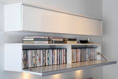 an entertainment center with several different types of cds on the shelves and lights below it