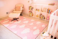 a baby's room is decorated in pink and white with clouds on the rug