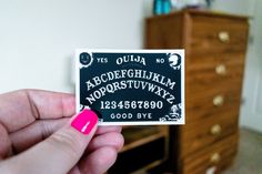 a person holding up a black and white sticker that says ouula, alphabet, and numbers