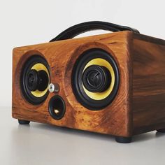 a wooden speaker with two speakers on it's front and back sides, sitting on top of a table