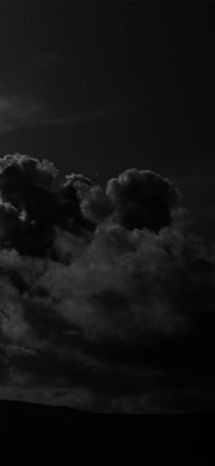 black and white photograph of clouds in the night sky with full moon behind it on an overcast day