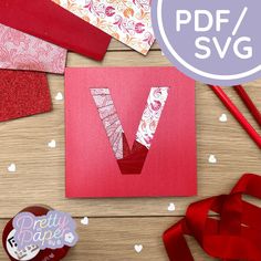 paper cut out into the shape of a v on top of a wooden table with red ribbon