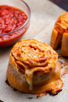 some kind of food that is sitting on a piece of parchment paper with sauce in the background