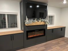 an empty room with a fireplace in the center and several cabinets around it, all decorated for christmas