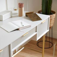 a white desk topped with a notebook and pencils