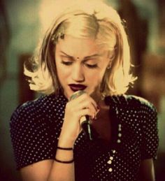 a woman holding a microphone in her right hand and wearing a polka dot shirt on the left