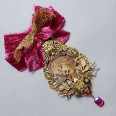 a pink and gold brooch with an image of a woman's face on it