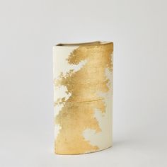 a gold and white vase sitting on top of a table