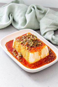 a square white plate topped with food on top of a table