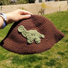 a crocheted hat with a green turtle on it is being held by someone