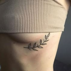 a woman's stomach with a small leaf tattoo on her left side ribcage