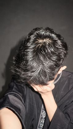 the back of a woman's head with her hand on her chin and hair in front of her face