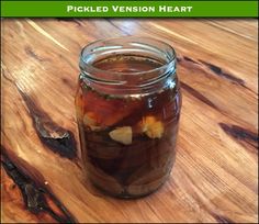 pickled venison heart in a mason jar on a wooden table with text overlay that reads pickled venison heart