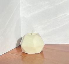 an apple sitting on the floor next to a white wall and wooden flooring area