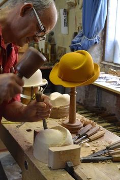 an older man working on a hat in his shop with woodworking tools around him