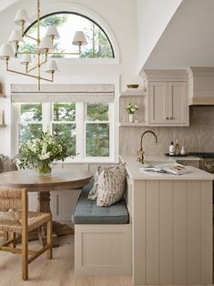 a kitchen with a table and chairs next to a window filled with flowers in vases