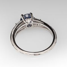 This finely detailed ring is centered with a four-prong set round brilliant cut natural blue sapphire. The split shoulders are each topped with one (1) channel set tapered baguette cut diamond. The shank is accented with four-rows of seven (7) bead set round brilliant cut diamonds. The profile of the ring is accented with one (1) bead set round brilliant cut diamond on each side. The ring measures 6.9mm at the top, rises 5.9mm above the finger, tapering to 2.1mm wide and 1.6mm thick at the base Classic White Gold Sapphire Ring With Baguette Cut, Classic Asscher Cut Sapphire Ring With Diamond Accents, Asscher Cut Sapphire Ring With Center Stone, Timeless Sapphire Ring With Asscher Cut For Formal Events, Timeless Asscher Cut Sapphire Ring For Formal Events, Asscher Cut Sapphire Ring With Diamond Accents, Sapphire Rings With Diamond Accents In Baguette Cut, Sapphire Rings With Diamond Accents And Baguette Cut, Brilliant Cut Asscher Sapphire Ring In Fine Jewelry