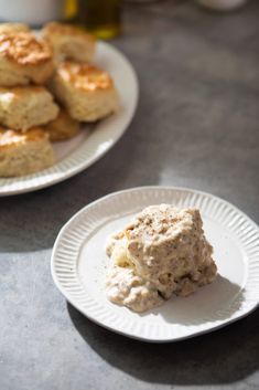 two plates with biscuits on them sitting on a table next to another plate full of biscuits