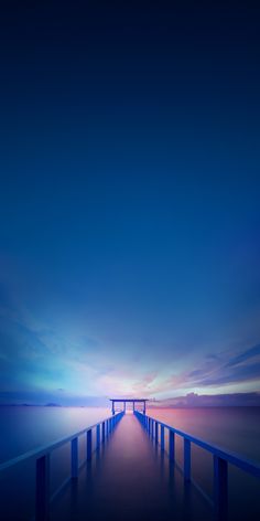 a long pier stretches out into the distance at dusk with blue sky and clouds in the background