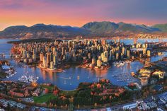 an aerial view of the city and its waterfront area at sunset, with mountains in the background