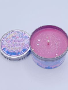 a pink candle in a tin on a white surface