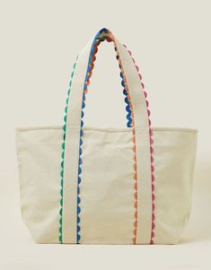 a white tote bag with colorful pom - poms on the handles and sides