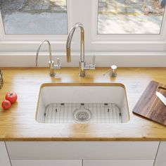 a kitchen sink sitting under a window next to a cutting board