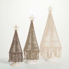 three small christmas trees with fringes and stars on top, one in white and the other in beige