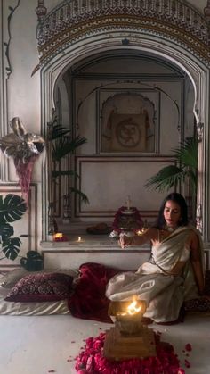 a woman sitting on top of a bed next to a pot with candles in it