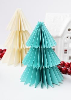 two paper christmas trees sitting next to each other on top of a white table with cranberries