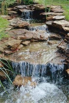 there is a small waterfall in the middle of some rocks and water flowing down it