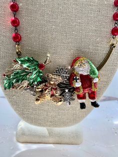 a necklace with christmas decorations on it and a santa clause figure hanging from the front