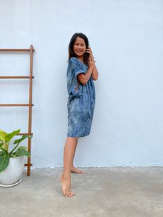 a woman standing in front of a white wall talking on a cell phone and smiling