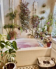 a bathtub filled with lots of plants next to a window