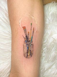 a woman's leg with a jar full of pencils and toothbrushes on it