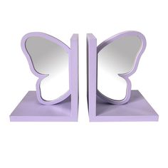 two purple butterfly shaped mirrors sitting on top of each other's sides, one is open and the other has its reflection in it