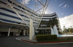 an office building with a fountain in front of it and palm trees on the other side