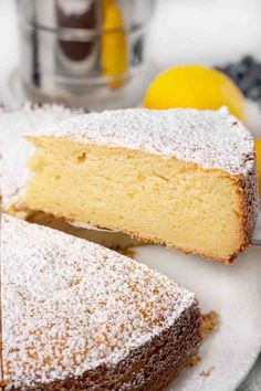 a slice of cake on a plate with powdered sugar and lemons in the background