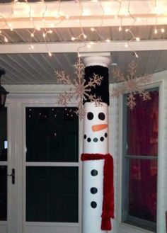 a tall snowman decorated with red and white lights in front of a door way