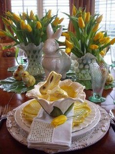 the table is set with yellow flowers and dishes